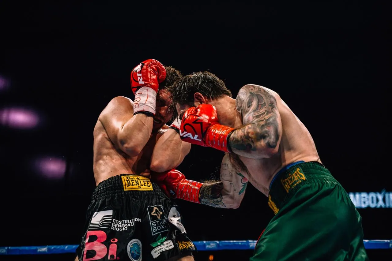 Two boxers trade punches at close range under the ring lights.